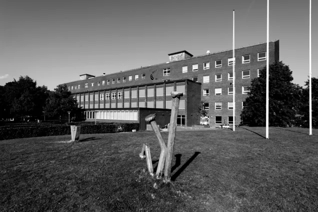 Black and white image of brick building with a sculpture in front. Photo.